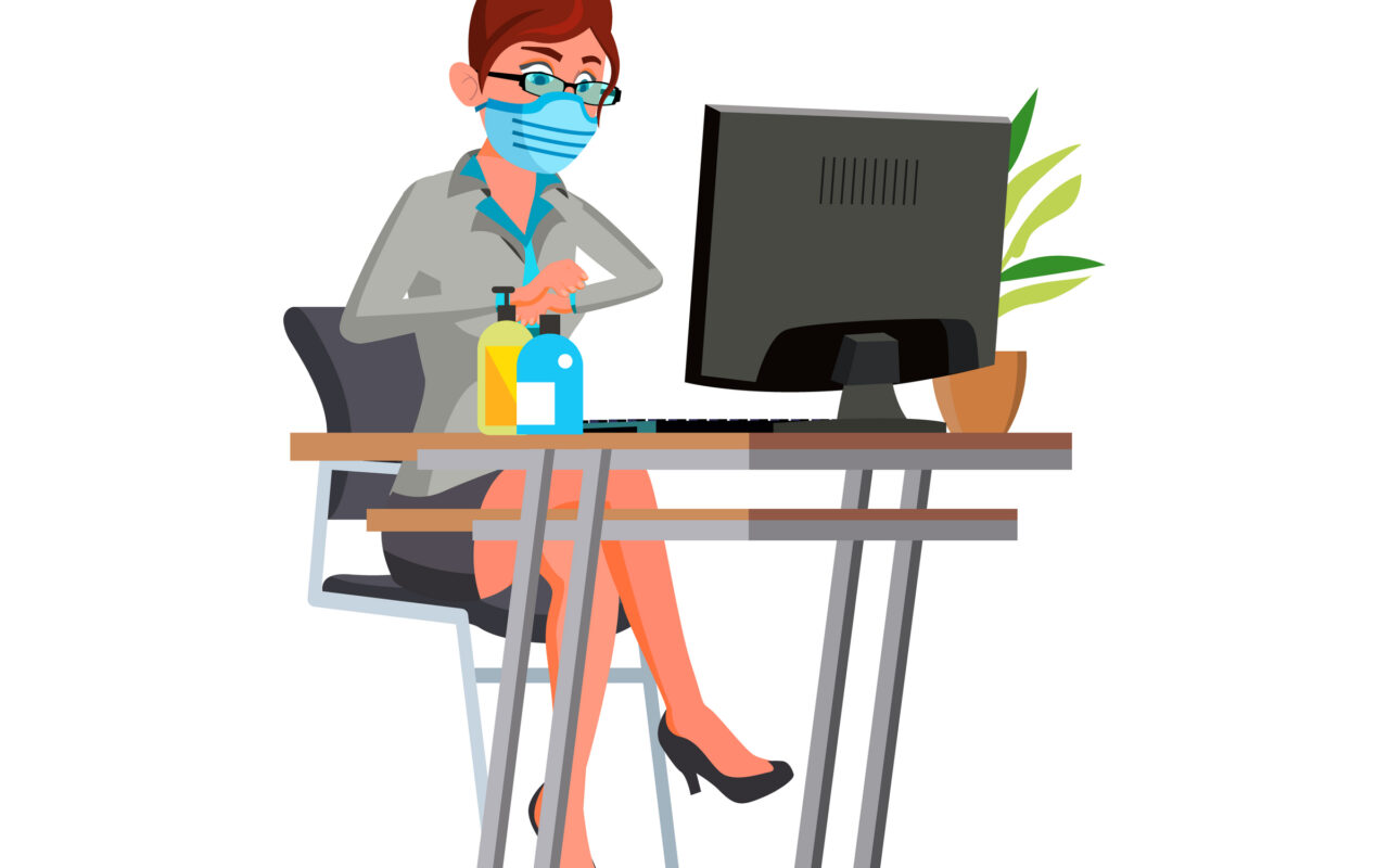 Woman in a face mask sits at a desk with a computer, hand sanitizer and lotion bottles on the desk, and a plant nearby.
