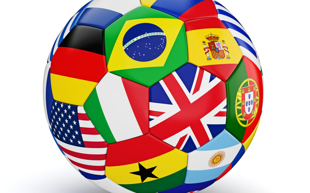 Soccer ball covered with patches of national flags, including Brazil, the United States, the United Kingdom, Spain, and Argentina in a colorful mosaic.
