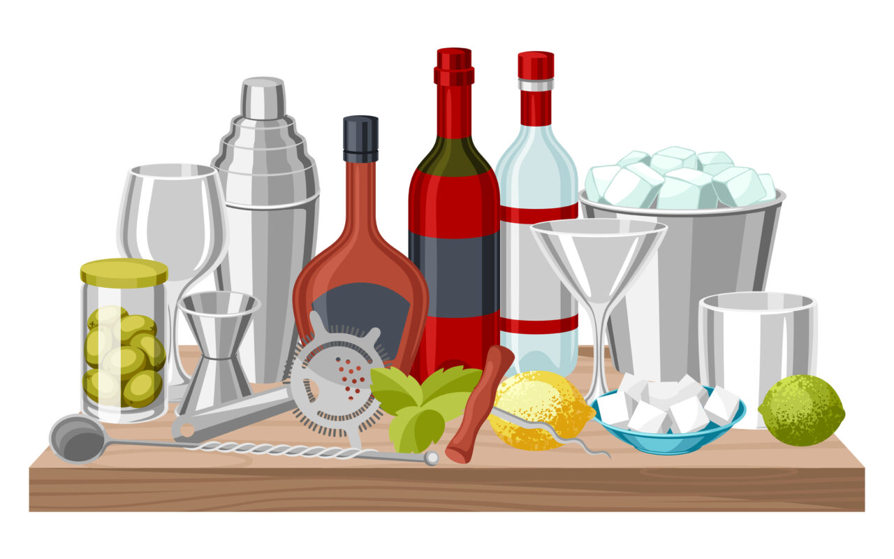 Bar toolkit on a wooden counter with bottles, shaker, jigger, strainer, glassware, lemon, mint, sugar, and ice bucket.