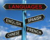 Signpost with arrows labeled LANGUAGES and English, Spanish, Chinese, and French against a blue sky.